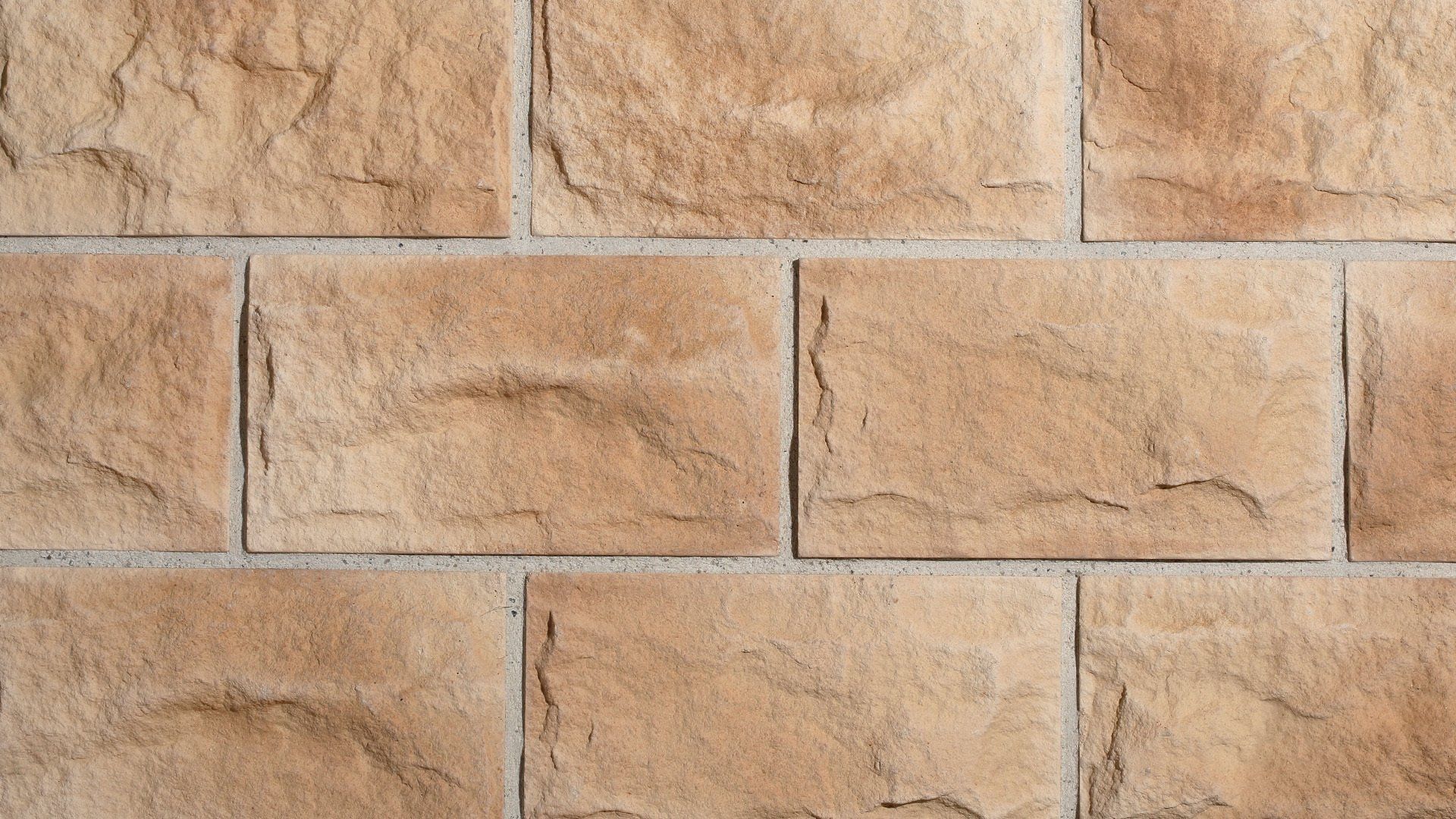 Tan rectangular stone bricks in a staggered pattern, with light gray grout lines.