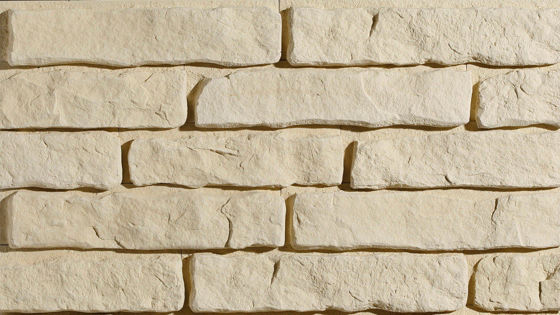 Close-up view of light beige brick wall with textured surface and visible mortar joints.