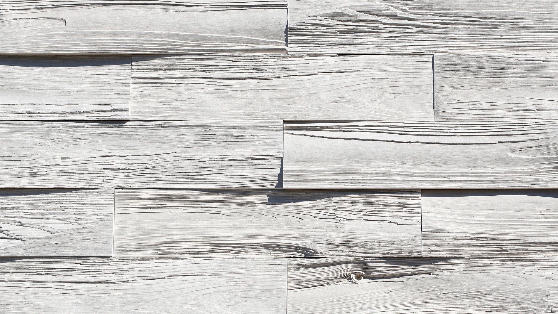 White, textured wall cladding made of rectangular blocks with horizontal, weathered grain patterns.