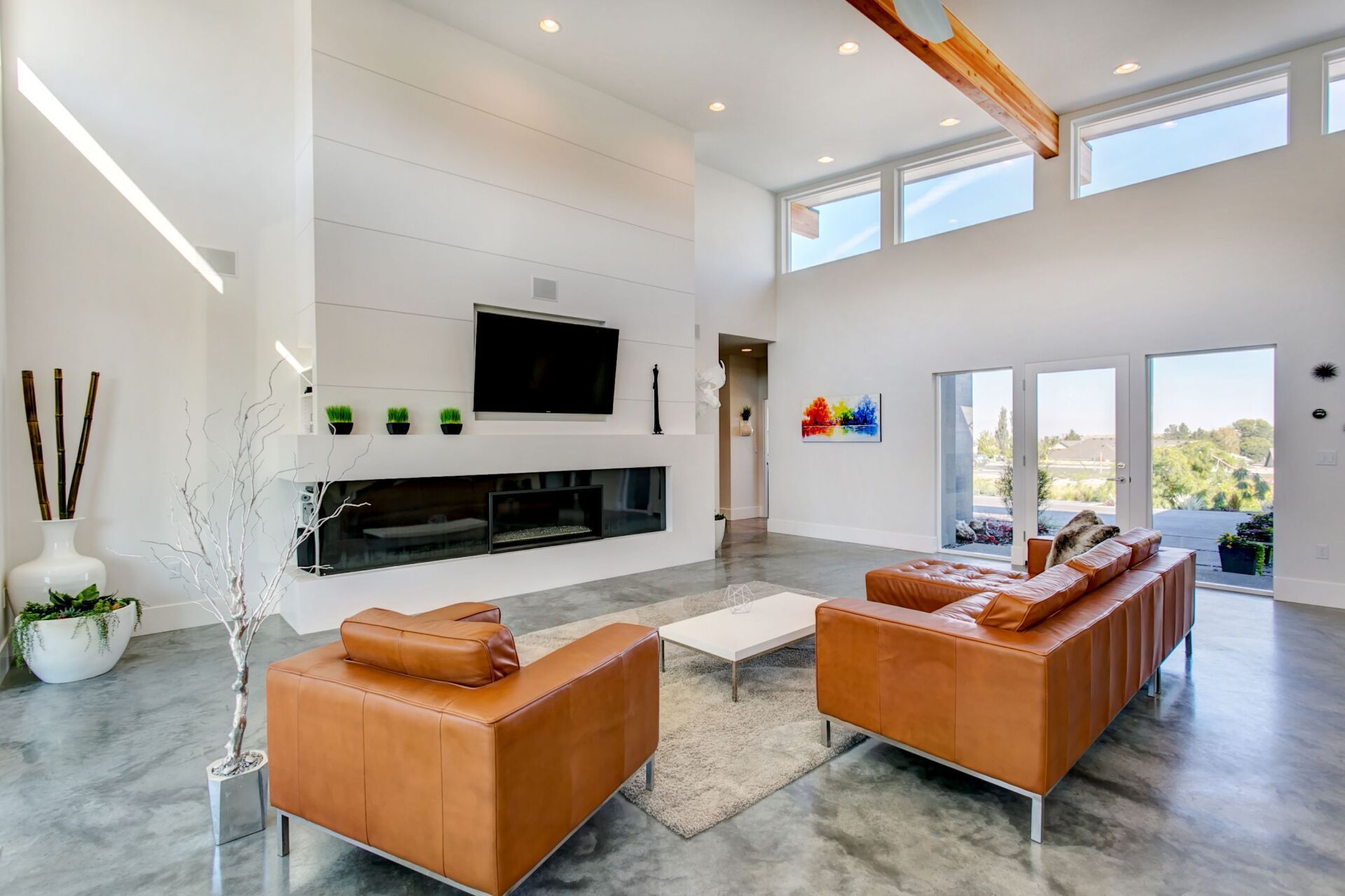 A living room with a couch , two chairs , a television and a fireplace.