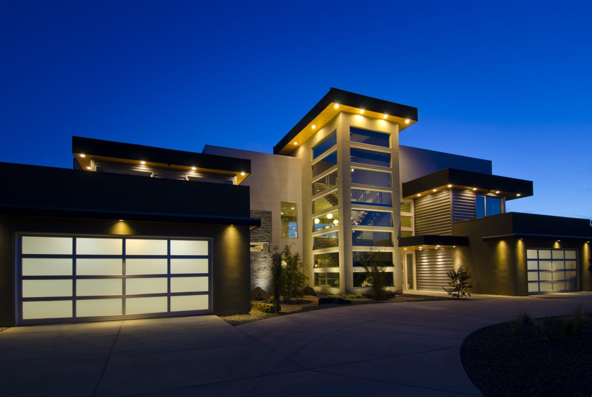 A large modern house is lit up at night