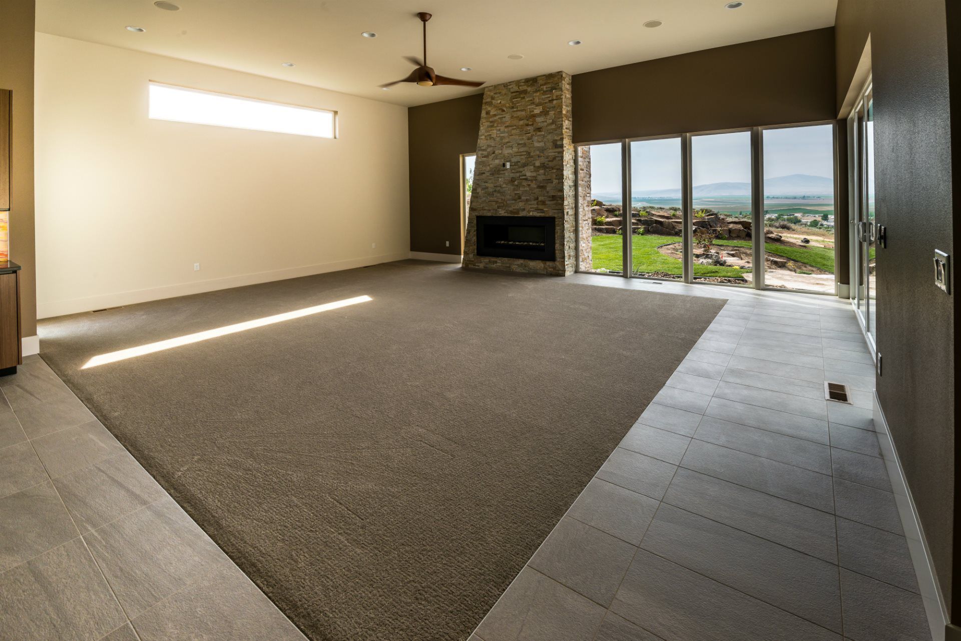 An empty living room with a fireplace and large windows