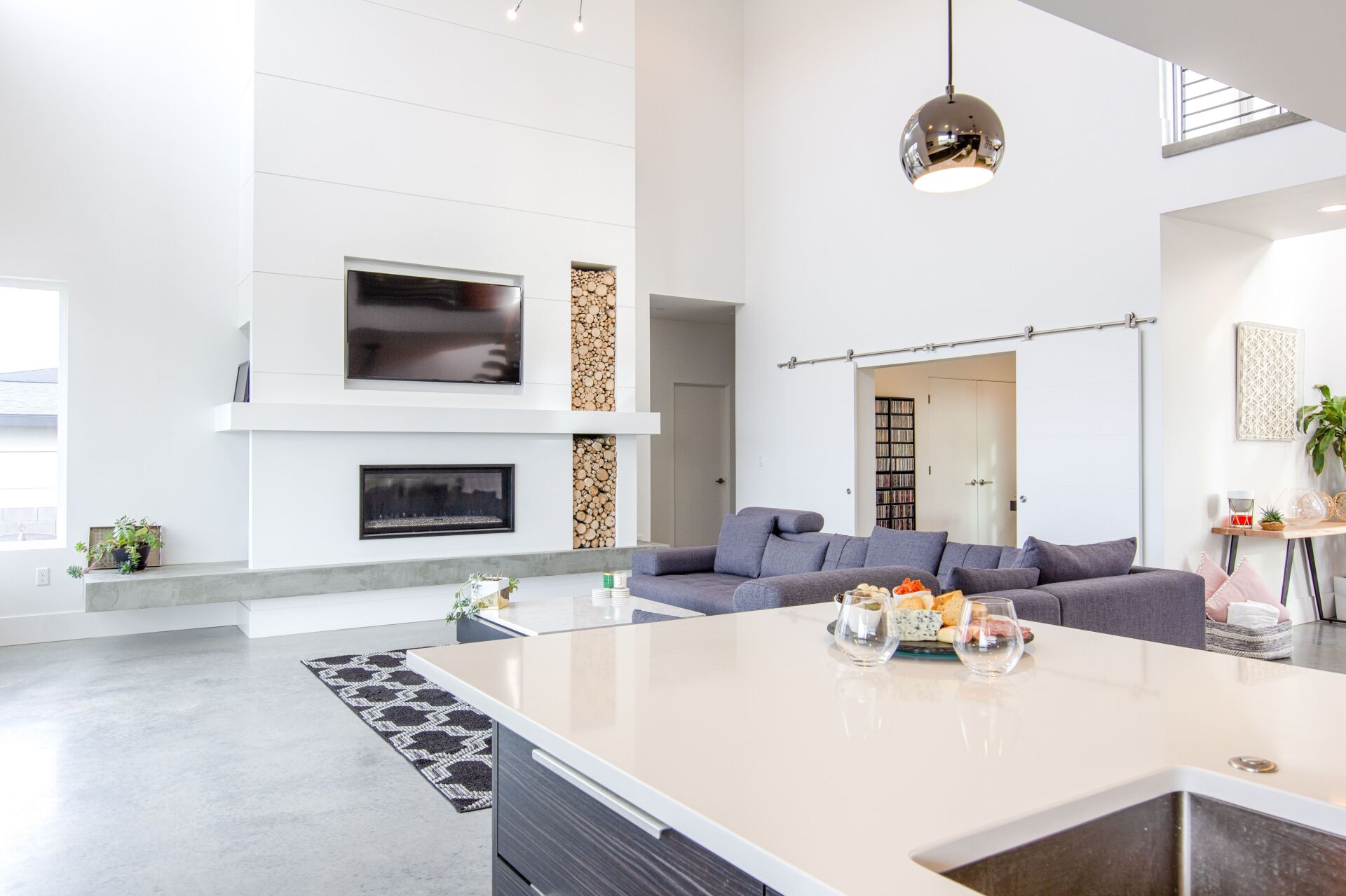 A living room with a couch , fireplace , television and a sink.