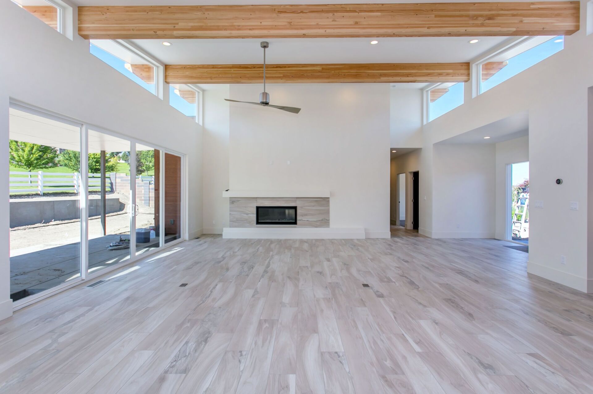 An empty living room with a fireplace and a ceiling fan