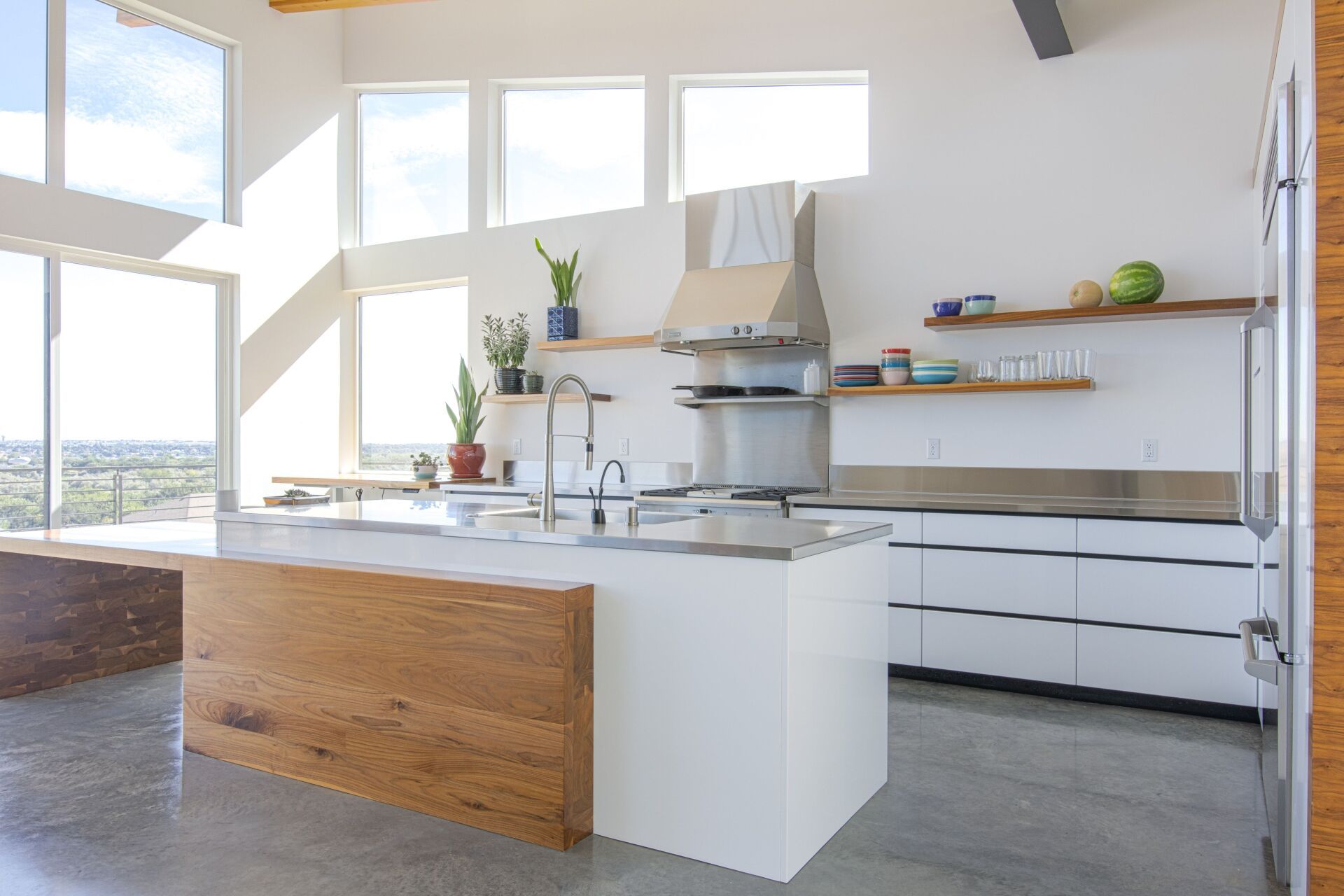 A kitchen with white cabinets , stainless steel appliances , and a large island.