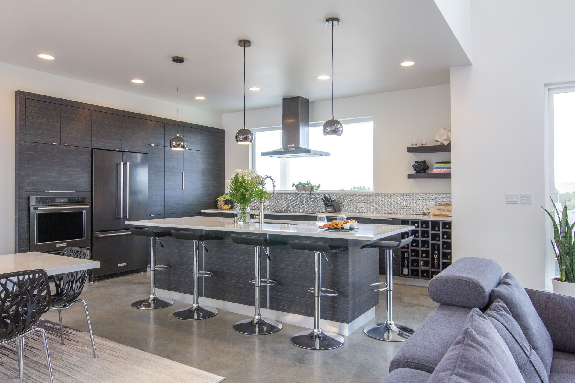 A kitchen with a large island , stools , a table and a refrigerator.