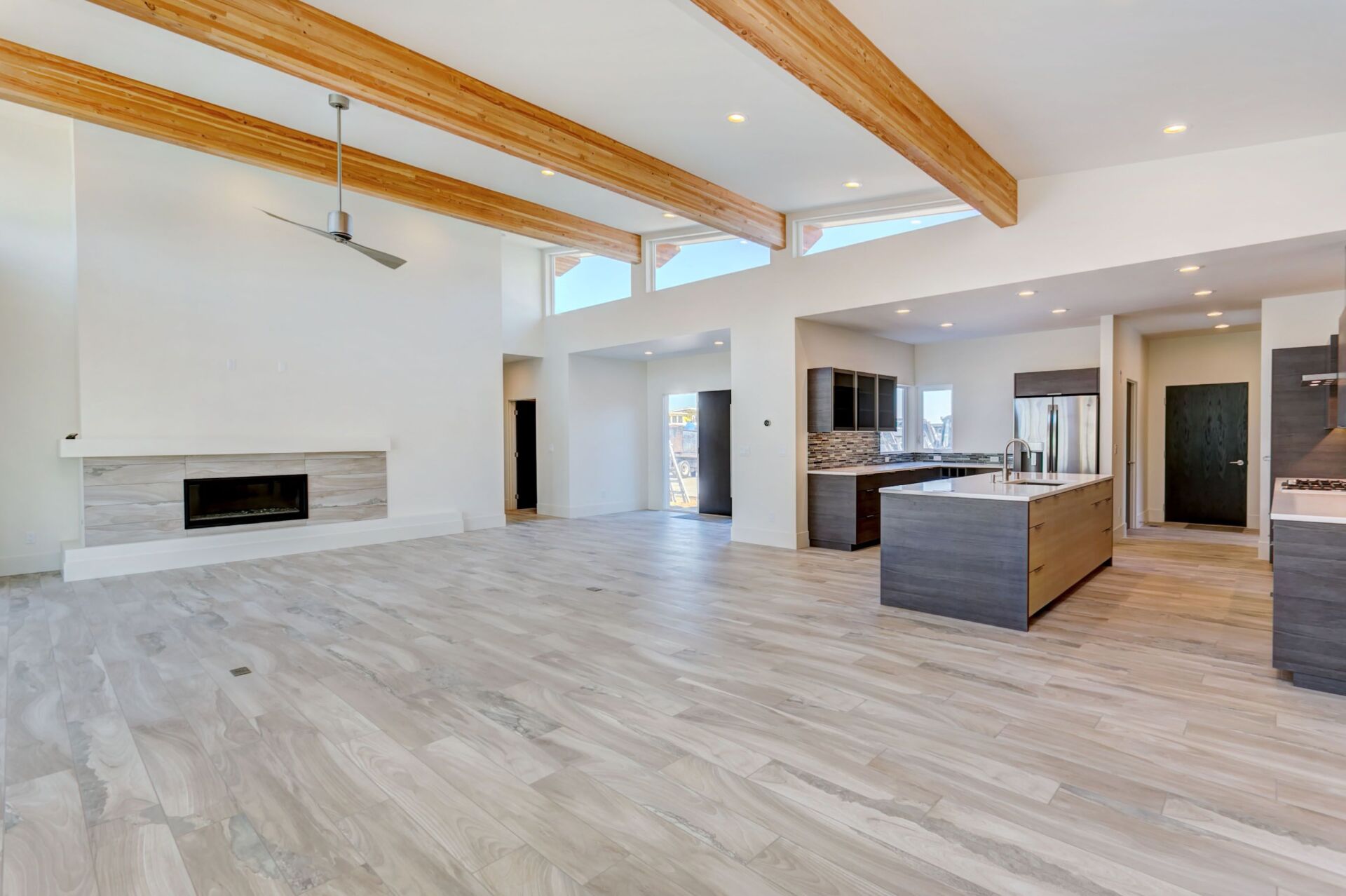 A living room with a fireplace and a kitchen in a house.