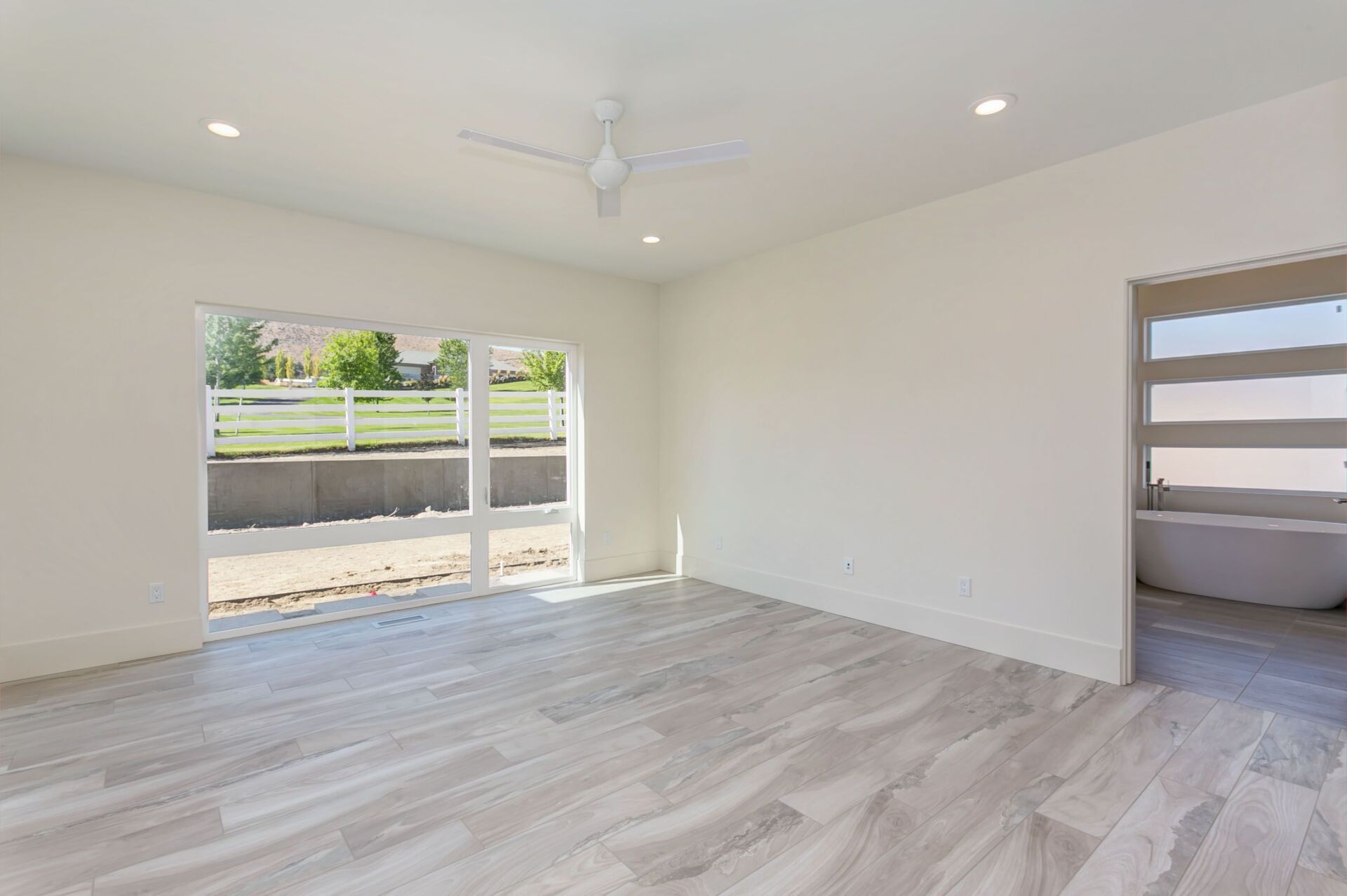 An empty living room with hardwood floors and a ceiling fan.