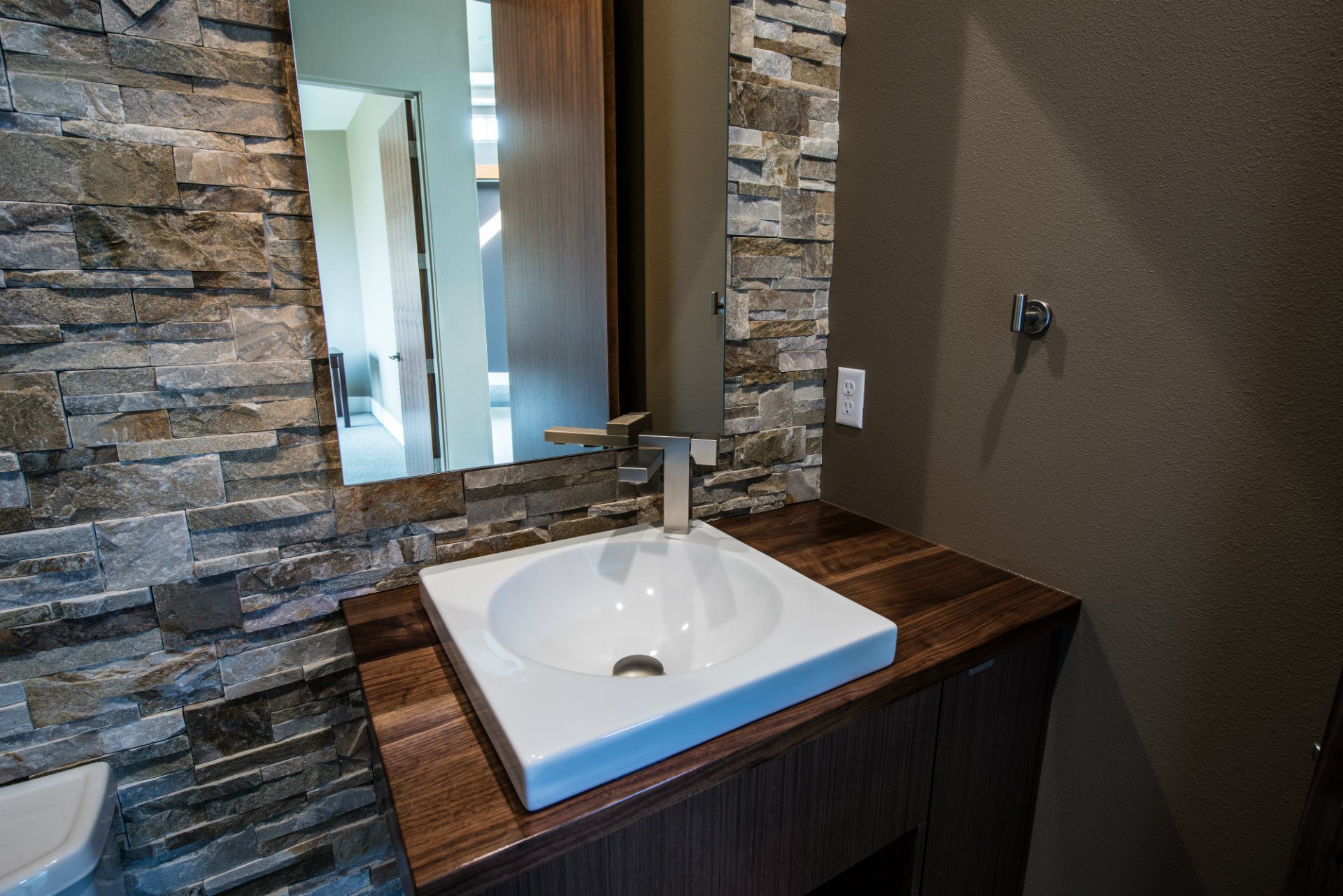 A bathroom with a sink , mirror and stone wall