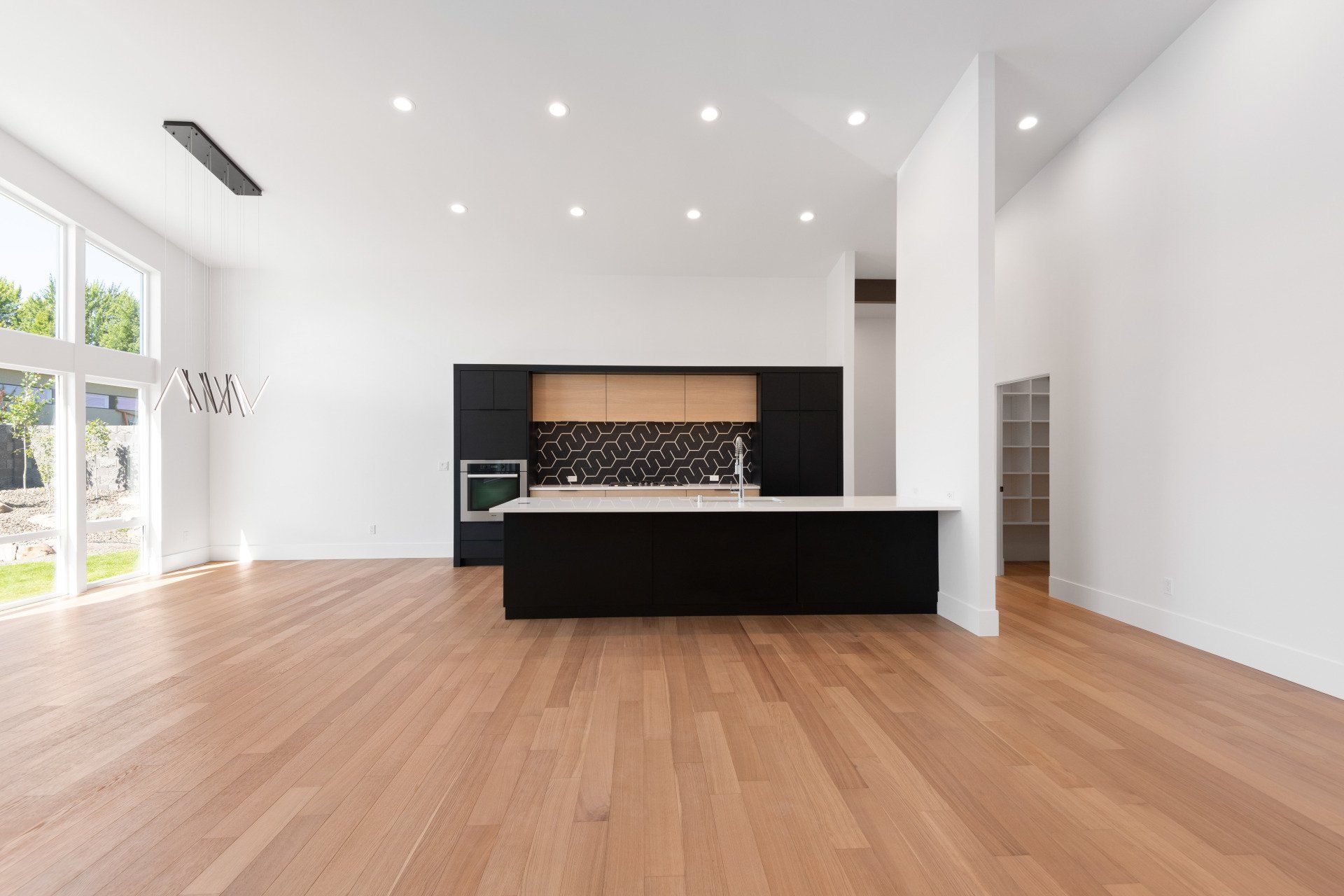 A large empty room with hardwood floors and a kitchen.