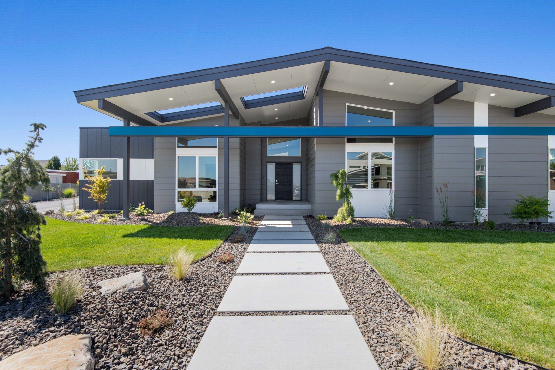 A modern house with a concrete walkway leading to it.