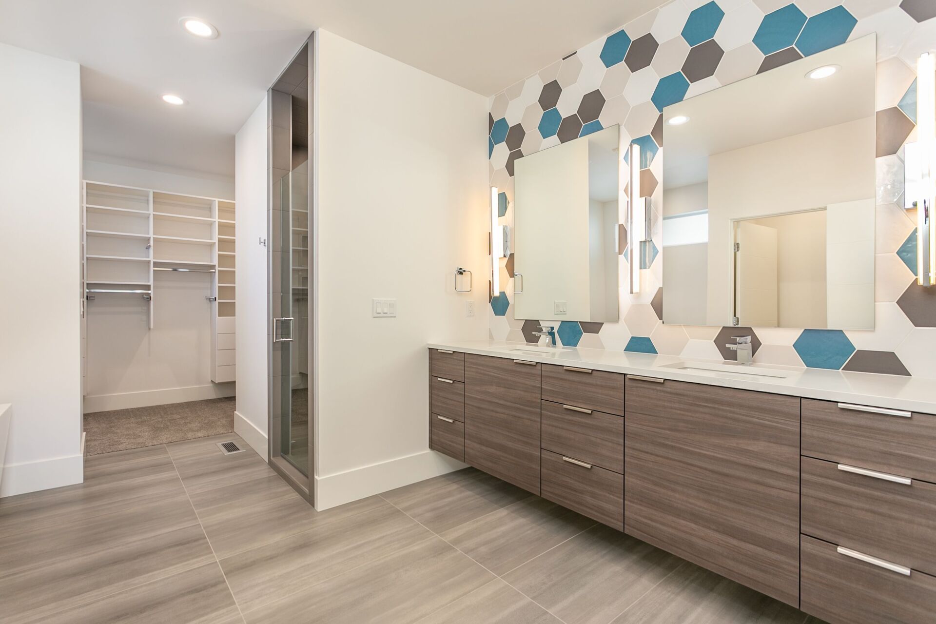 A bathroom with two sinks , a mirror and a walk in closet.