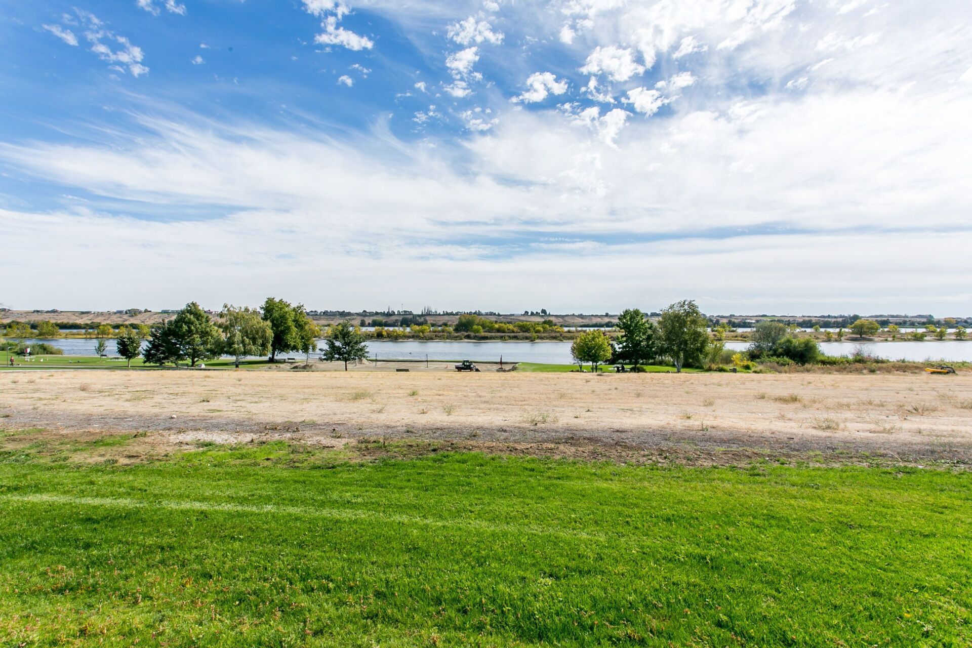 A large grassy field with a lake in the background.