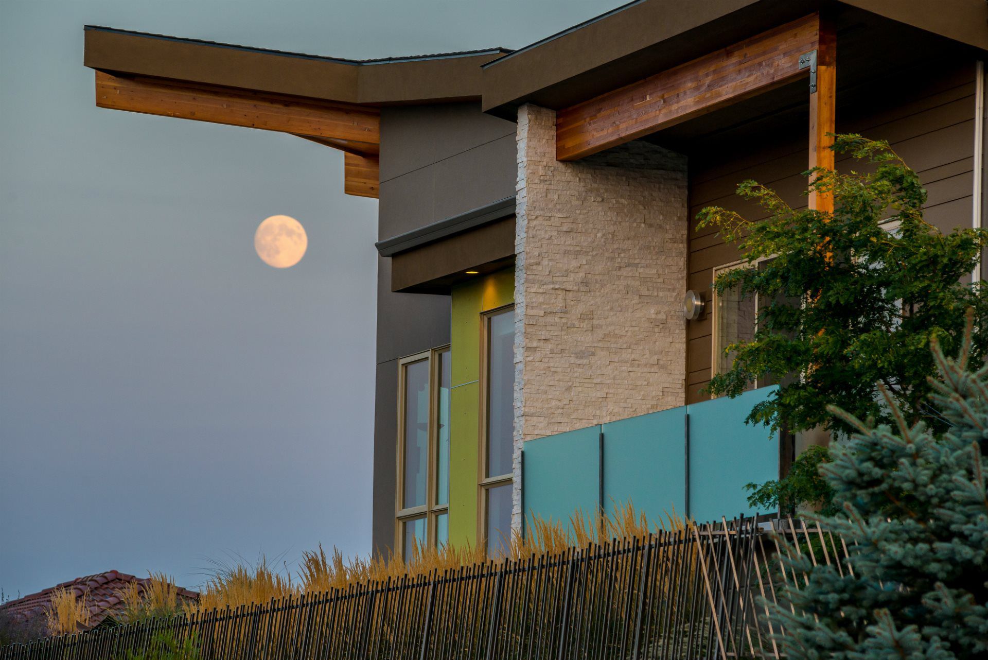 A full moon is rising over a modern house.
