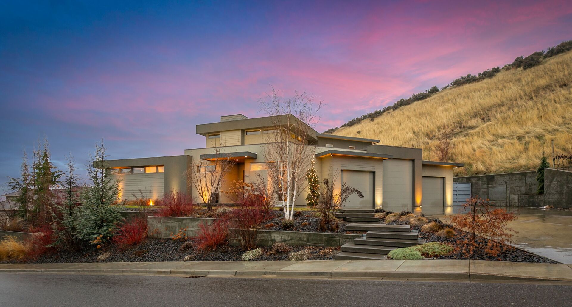 A large modern house is sitting on top of a hill.