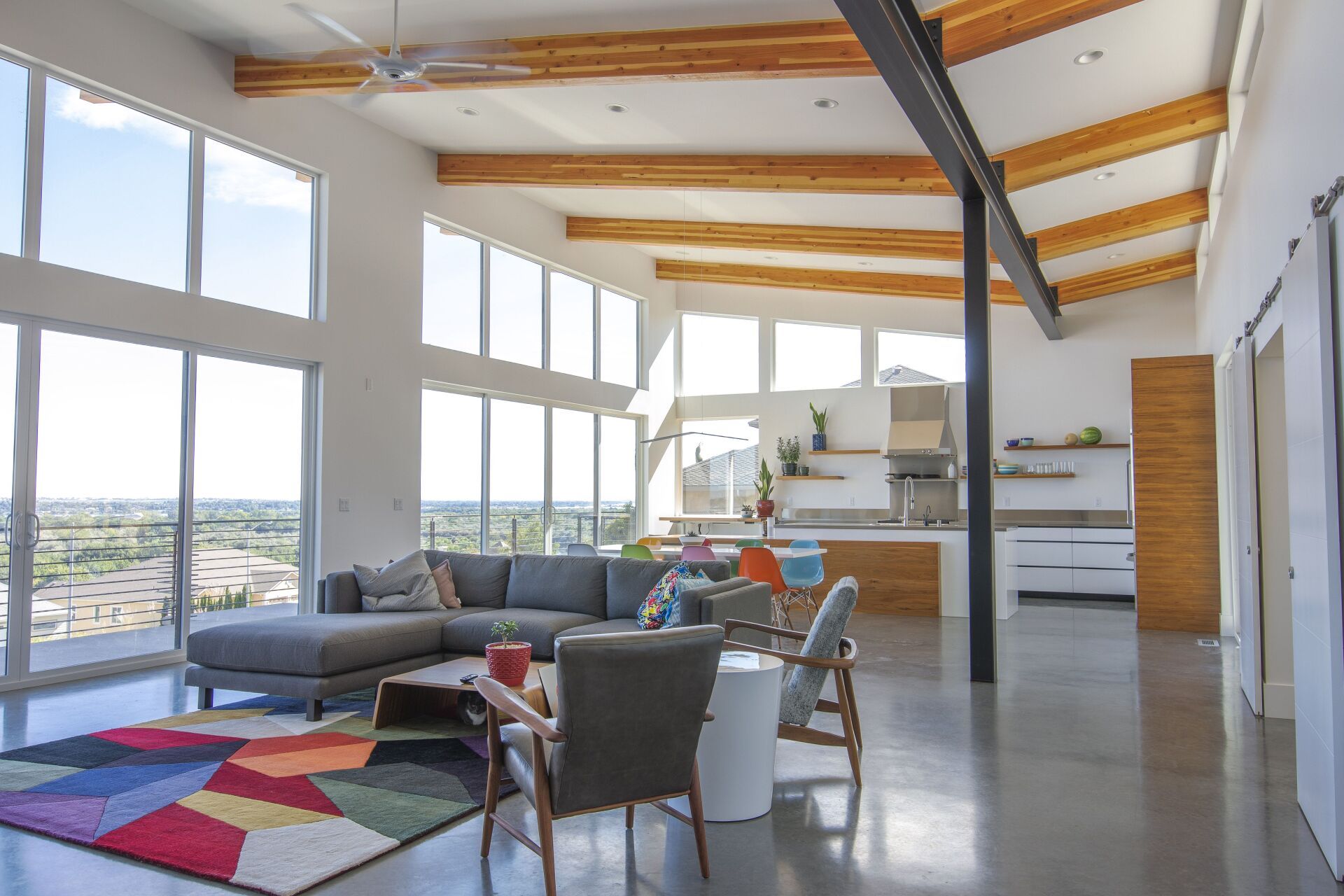 A living room with a couch , chairs , a rug and a ceiling fan.