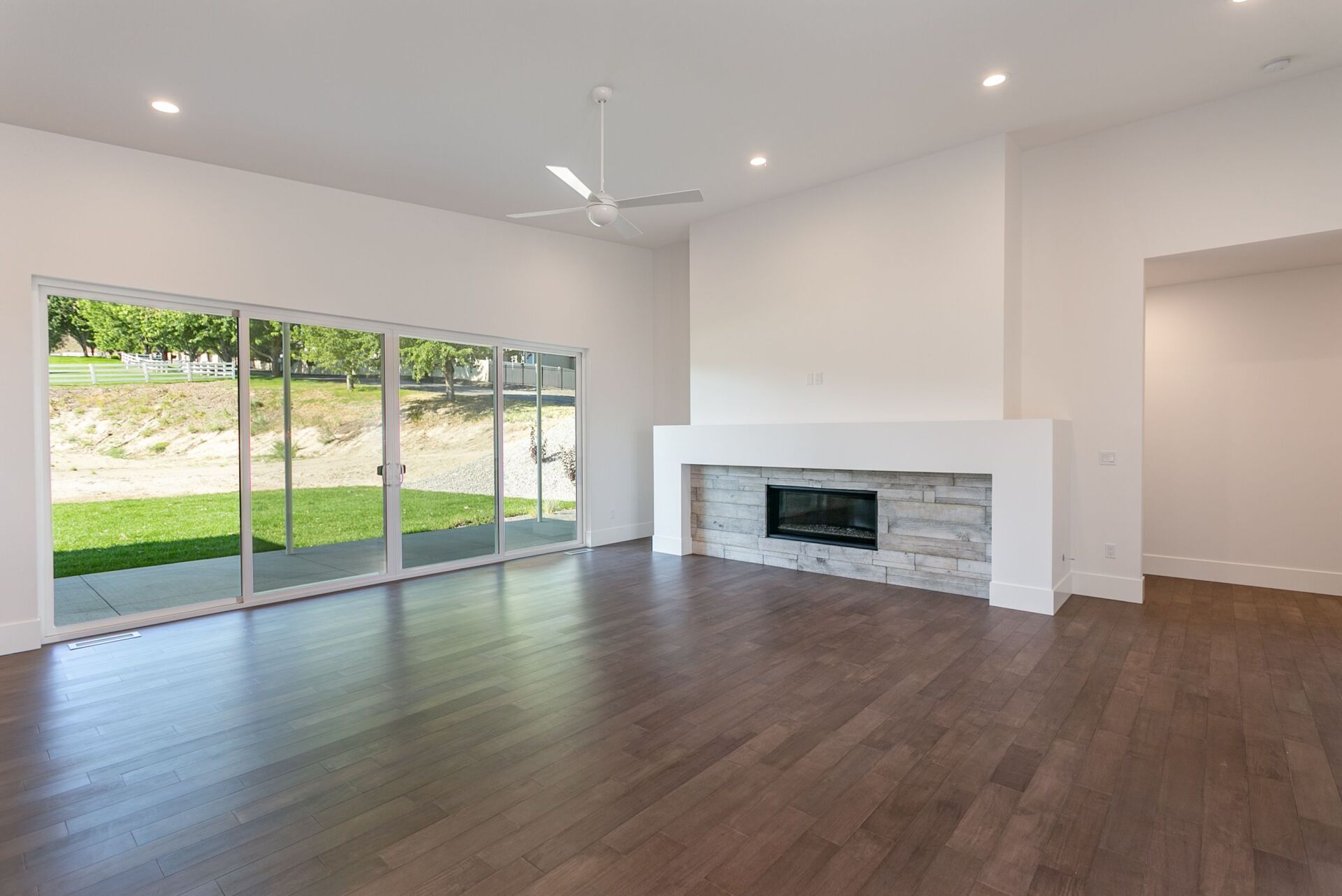 An empty living room with hardwood floors and a fireplace.