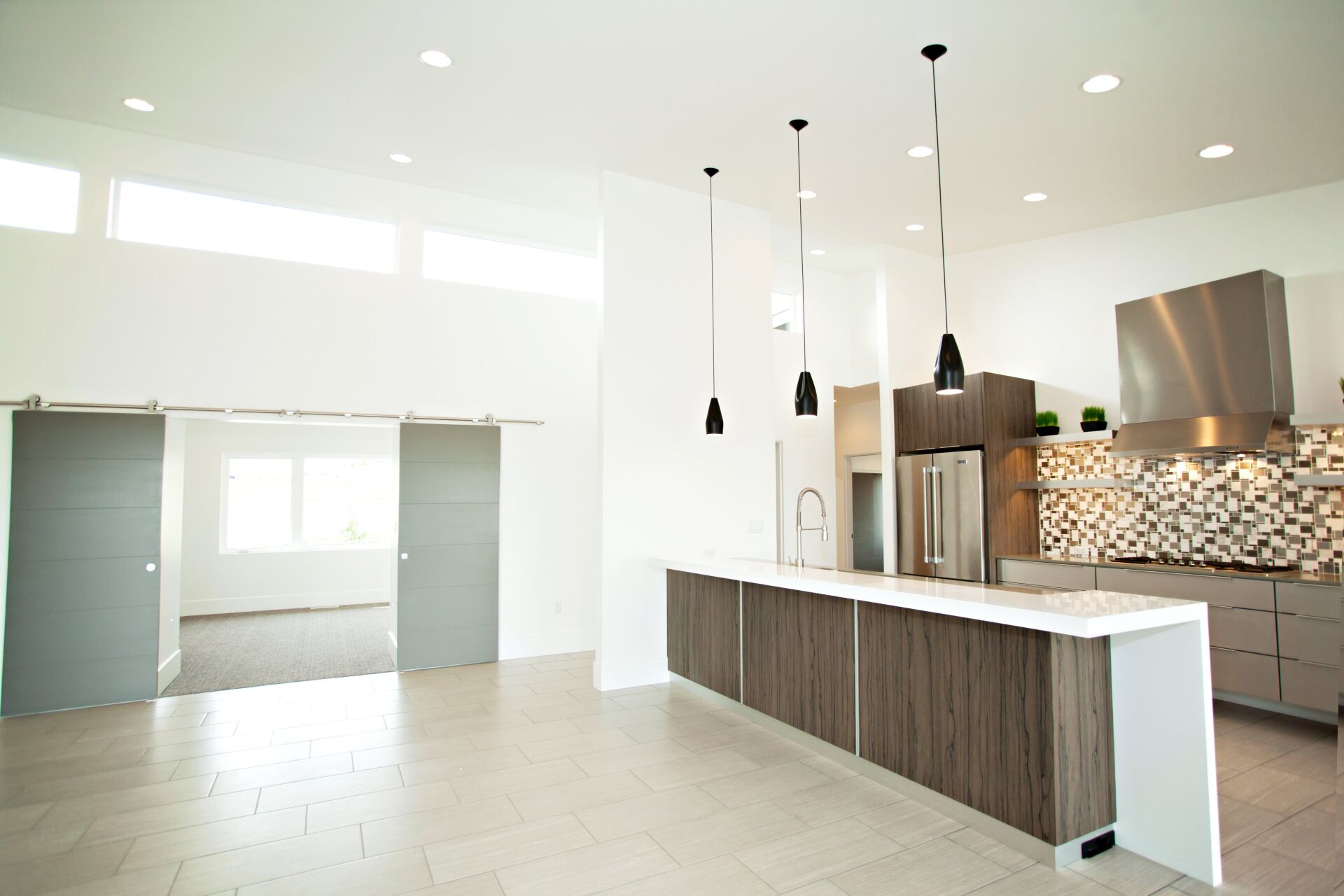 An empty kitchen with a large island and stainless steel appliances
