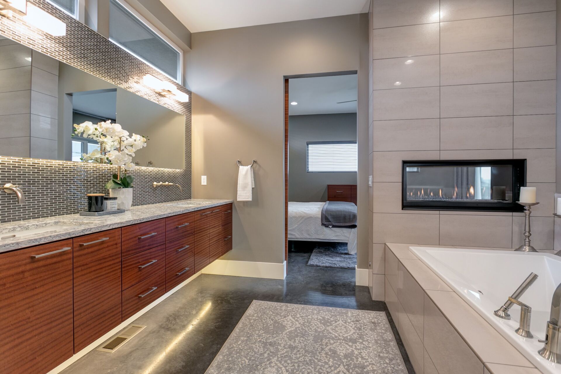 A bathroom with a tub , sink , mirror and fireplace.