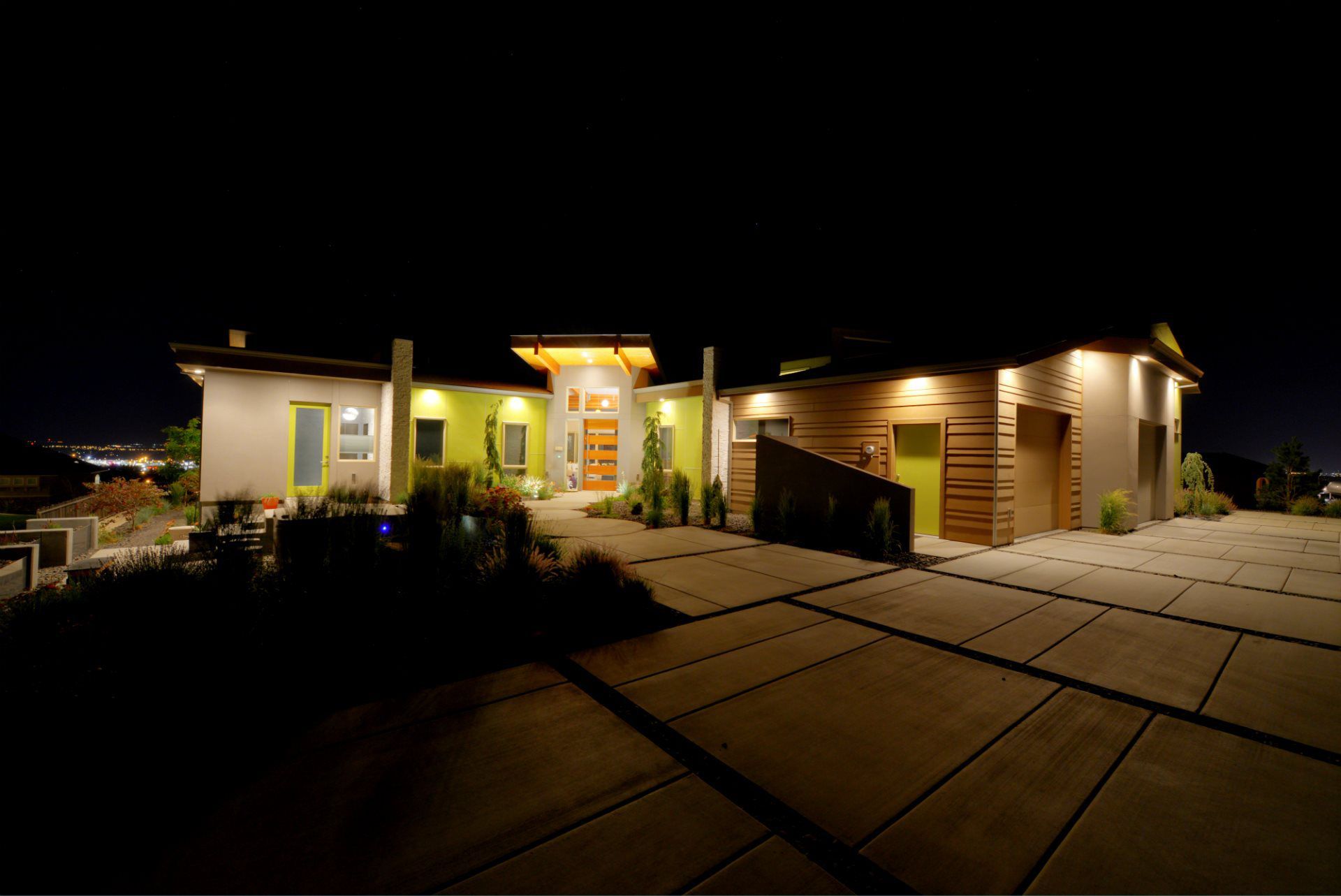A large house is lit up at night with a driveway in front of it.