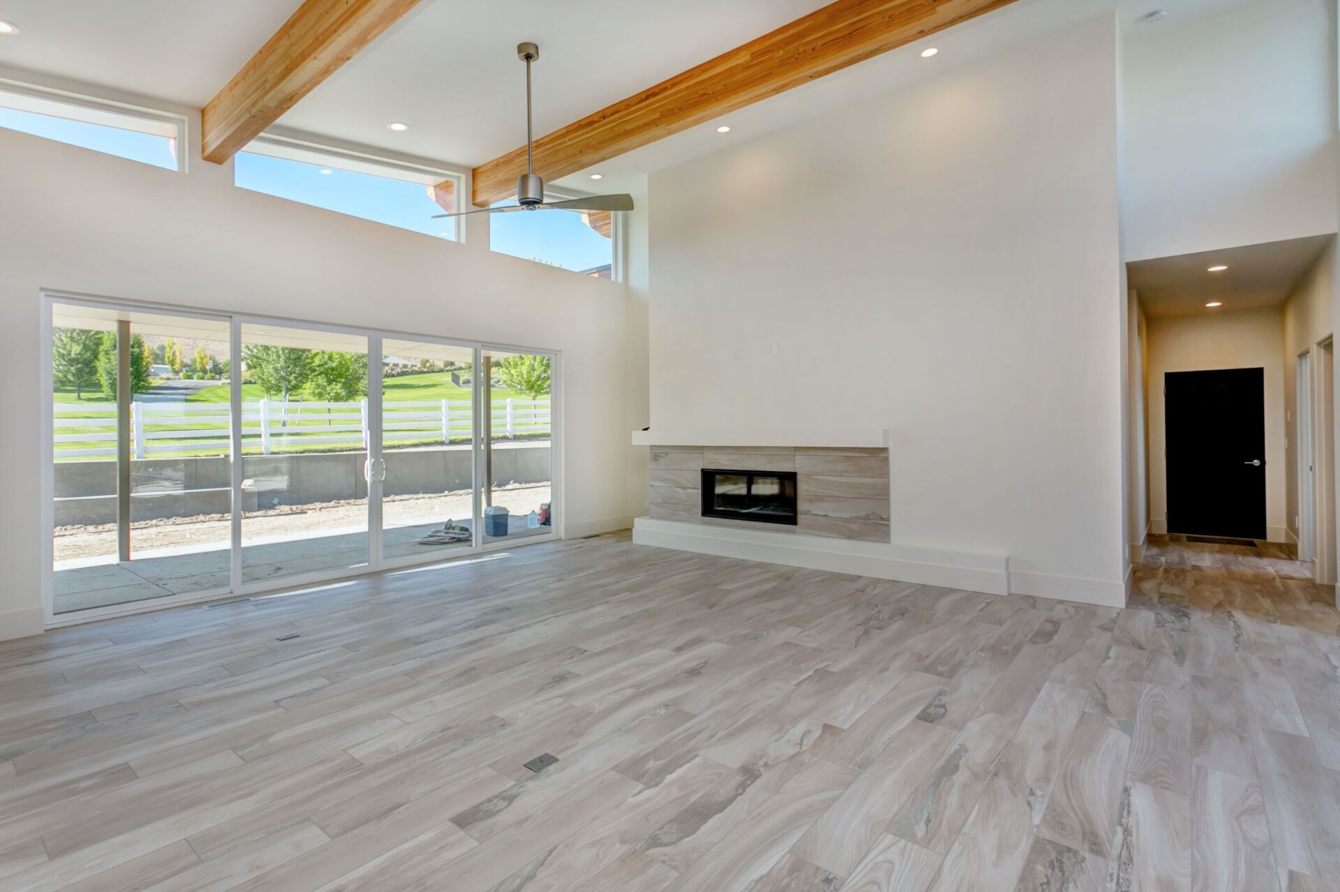 An empty living room with a fireplace and sliding glass doors.