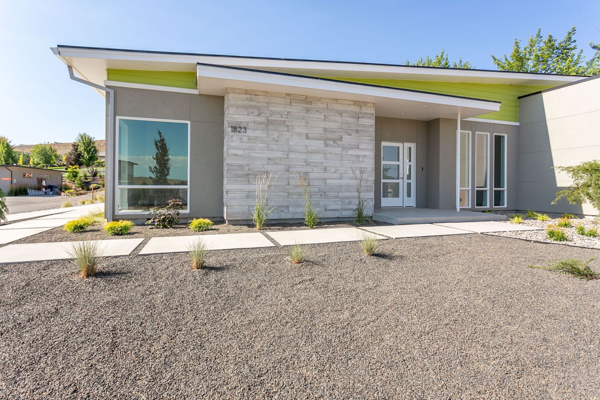 A modern house with a lot of windows and gravel in front of it.