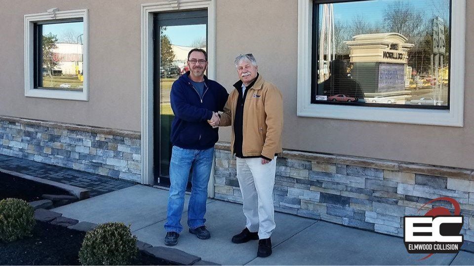 Owner, Michael Zwelling, shaking a customer's hand outside autobody shop