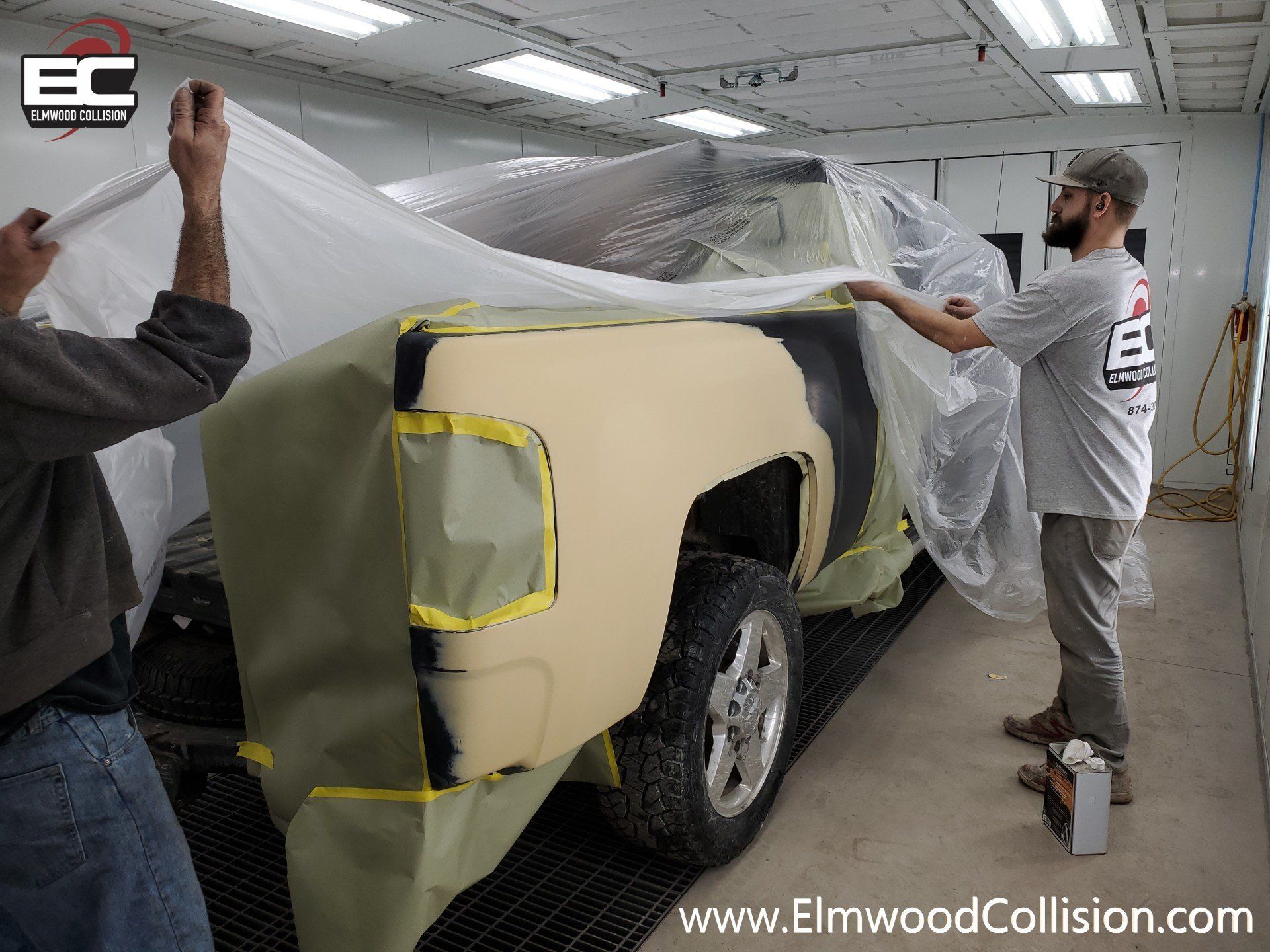 Truck getting covered in plastic in booth before painting