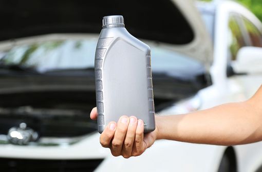A mechanic holding up an oil container
