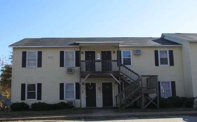 Small, two-story apartment building with yellow siding and blue shutters