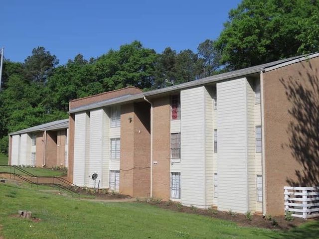Three-story apartment building with white siding and brick combo exterior