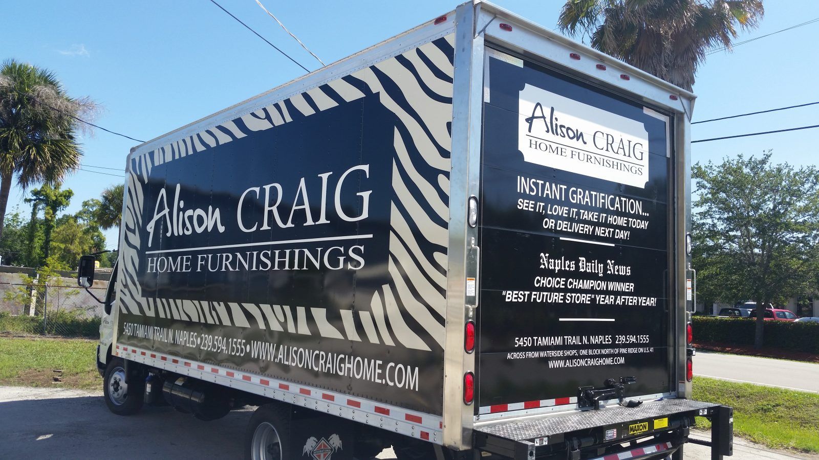 A moving truck with a zebra print is parked on the side of the road.
