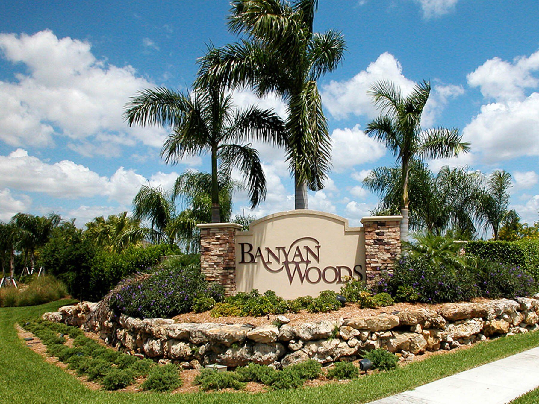 A sign for banyan woods is surrounded by palm trees
