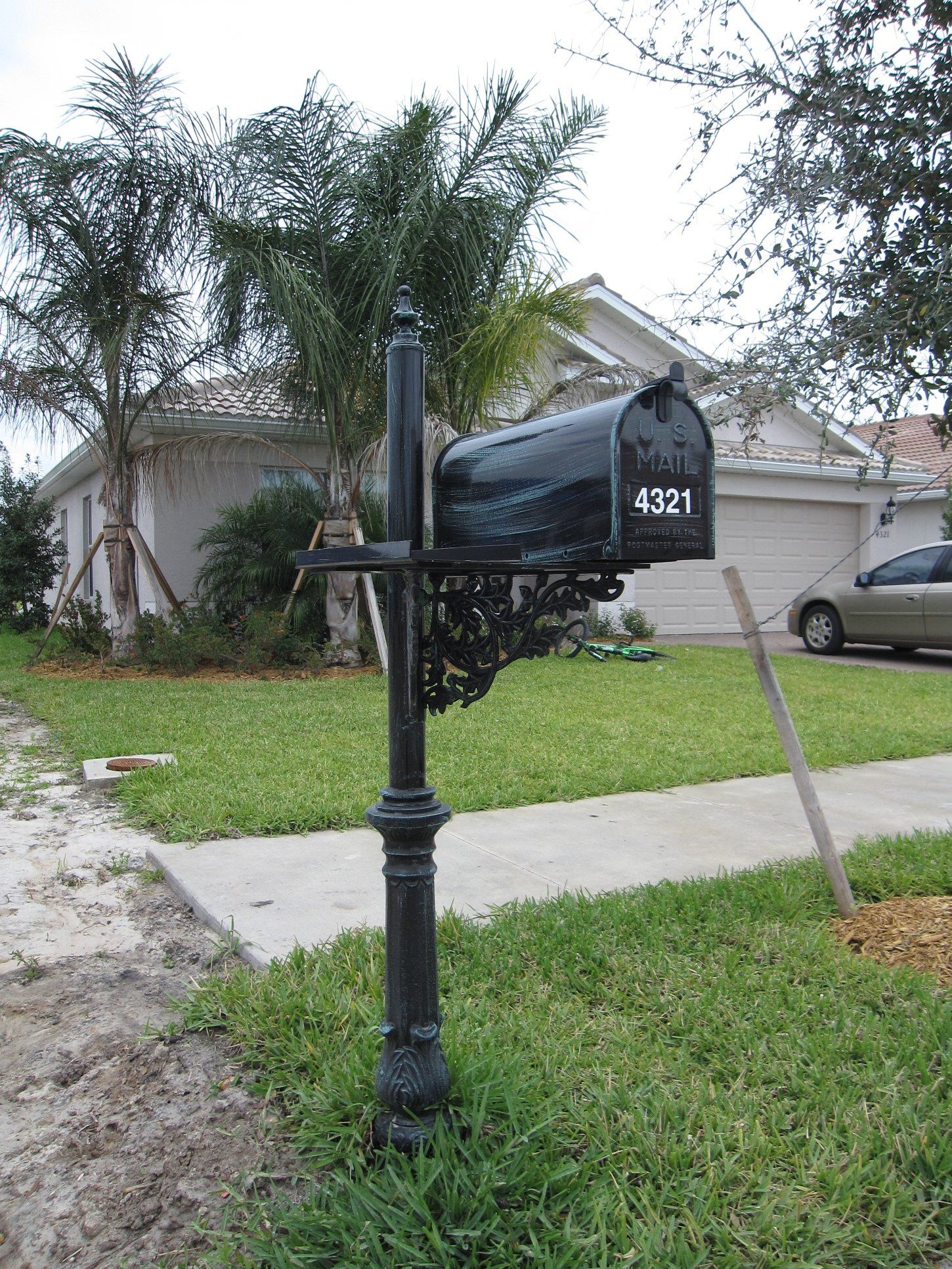 An aluminum decorative mailbox painted black  with green drybrush.