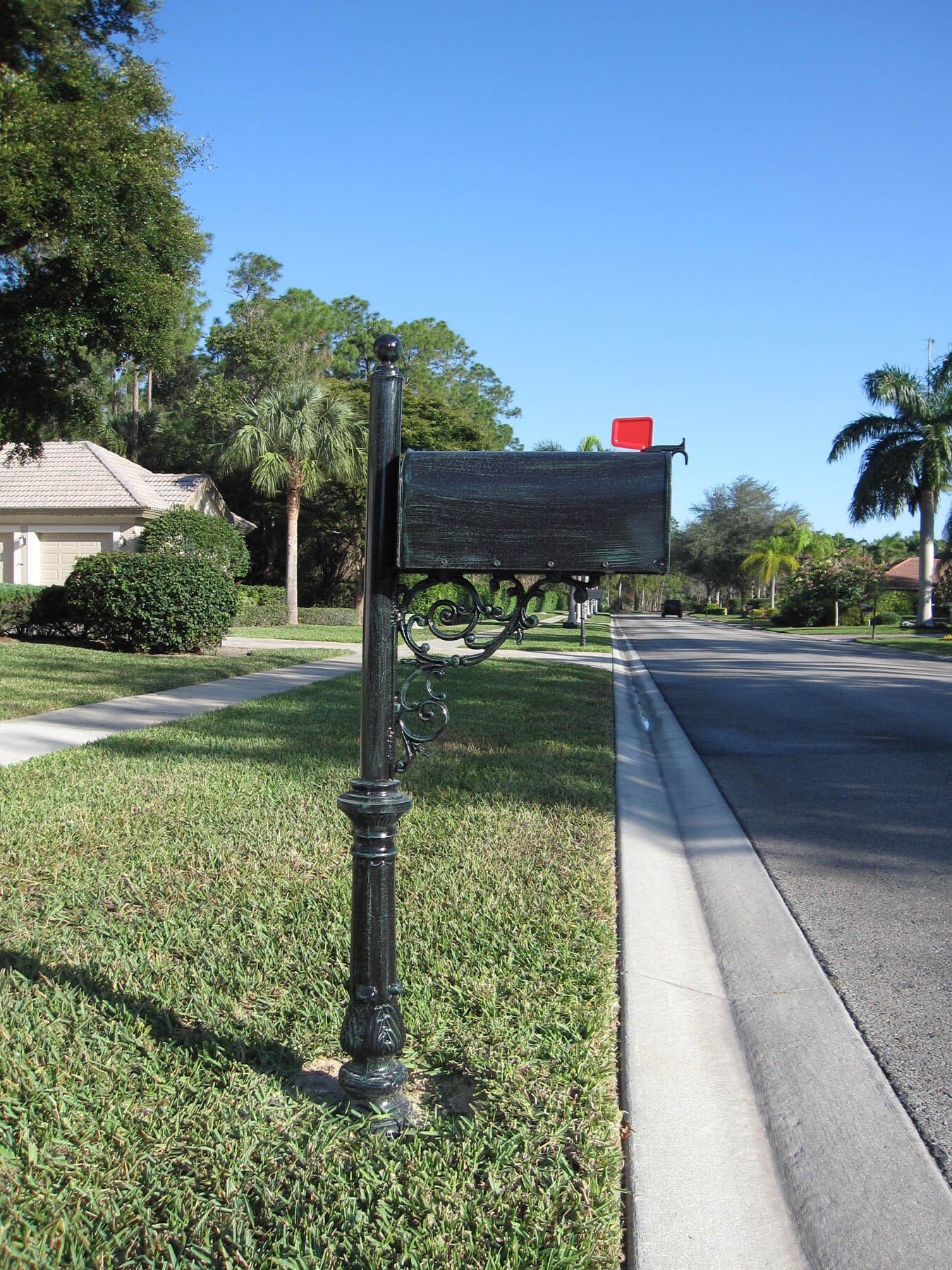 An aluminum decorative mailbox painted black  with green drybrush.