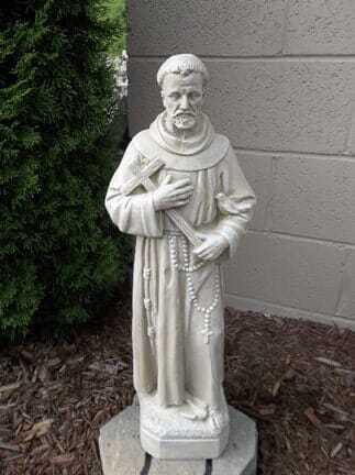 A statue of a monk holding a cross and a rosary.