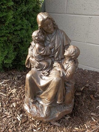 A bronze statue of jesus holding two children.