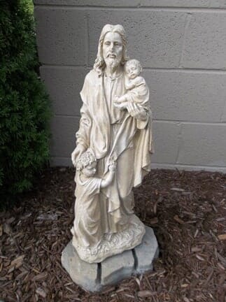 A statue of jesus holding a baby and a child.