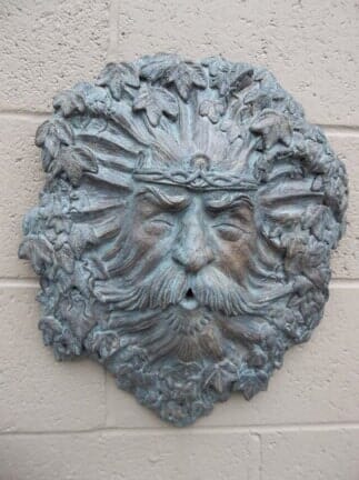 A statue of a man with a beard and mustache is hanging on a brick wall.