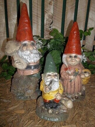 A couple of gnomes standing next to each other in front of a fence.