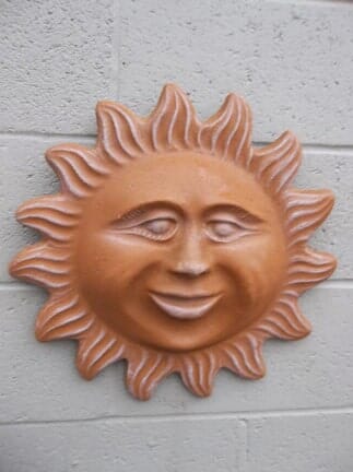 A sun with a face on it is on a brick wall