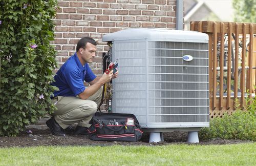 A man is working on an air conditioner outside of a house.