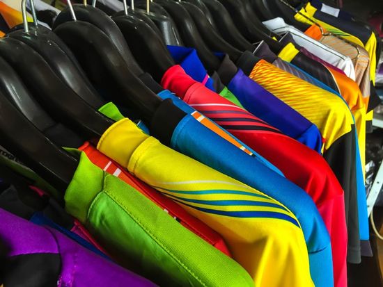 delle magliette colorate su degli appendini