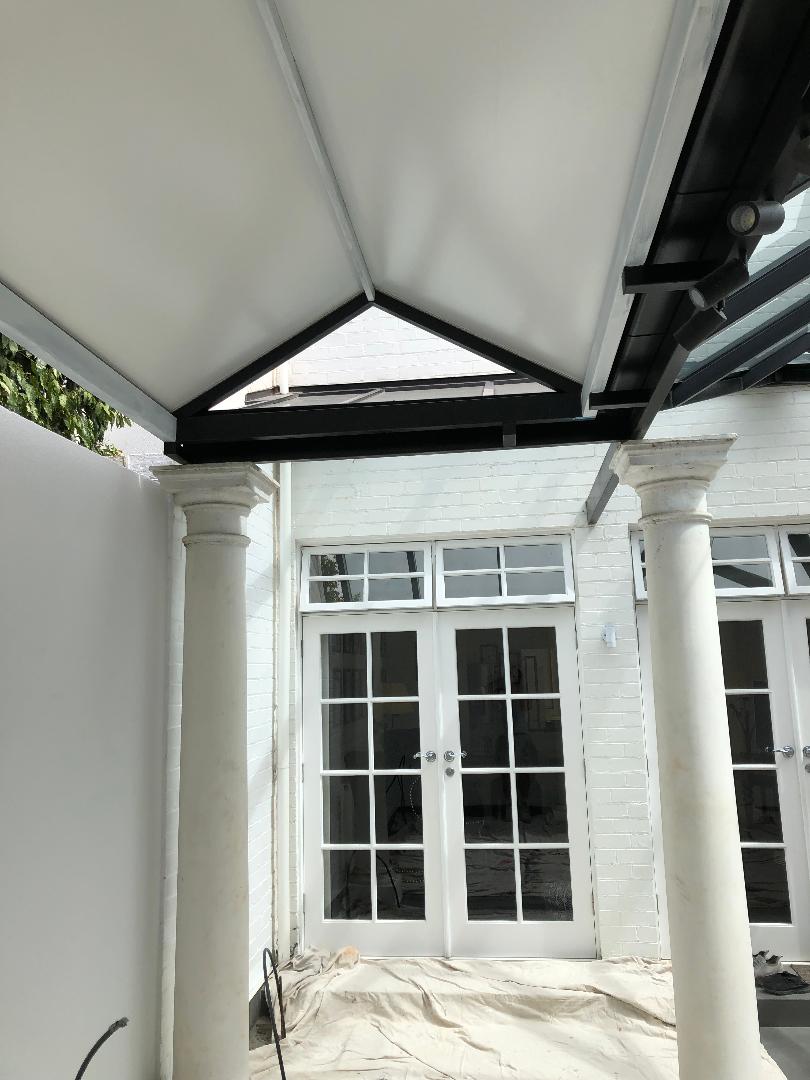 Covered patio with white columns and glass French doors leading to a house entrance
