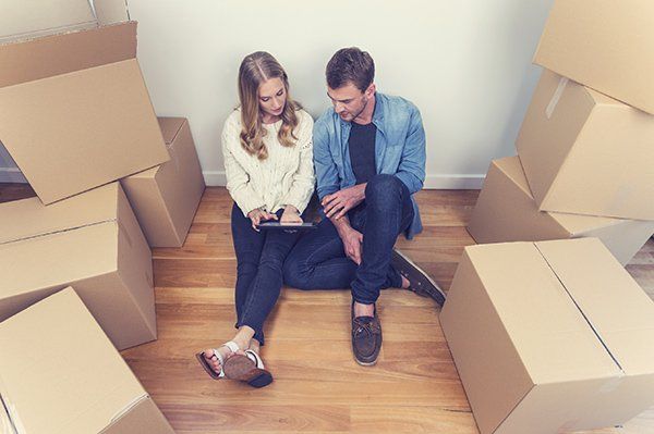 A couple looks at a tablet surrounded by boxes.