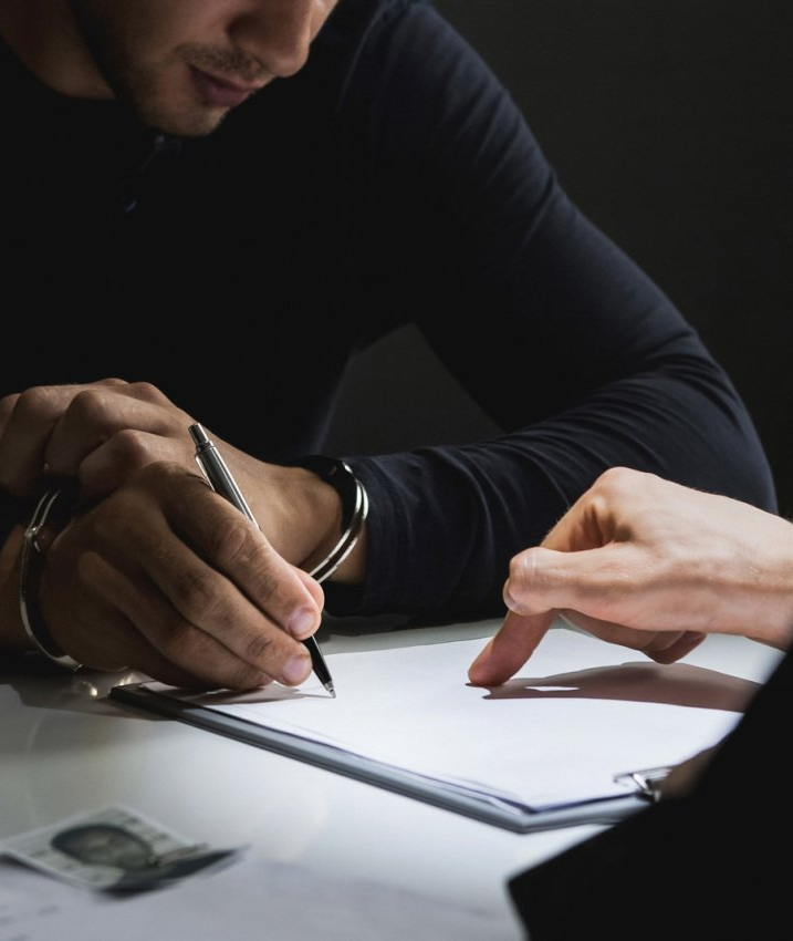 Criminal Law — Criminal Man with Handcuffs Signing Document in Bakersfield, CA