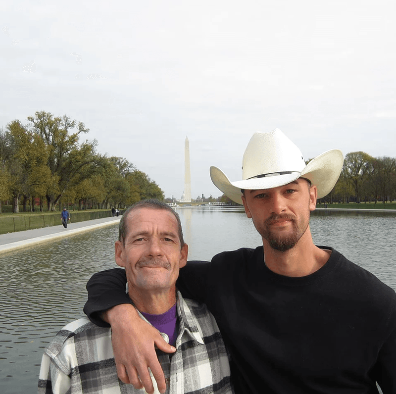 Two men posing for a picture with one wearing a cowboy hat