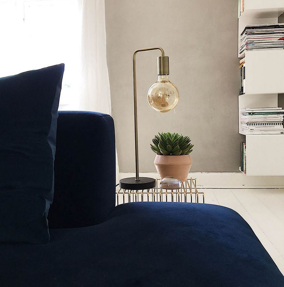 Eine Lampe steht auf einem Tisch neben einem blauen Sofa