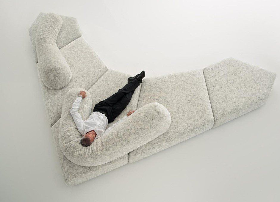 Ein Mann liegt auf einem großen weißen Sofa.