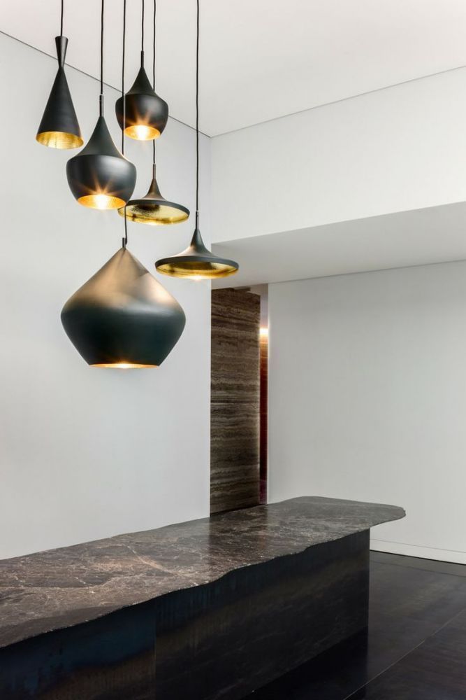 Schwarze und goldene Pendelleuchten, die von der Decke über einer Theke hängen
